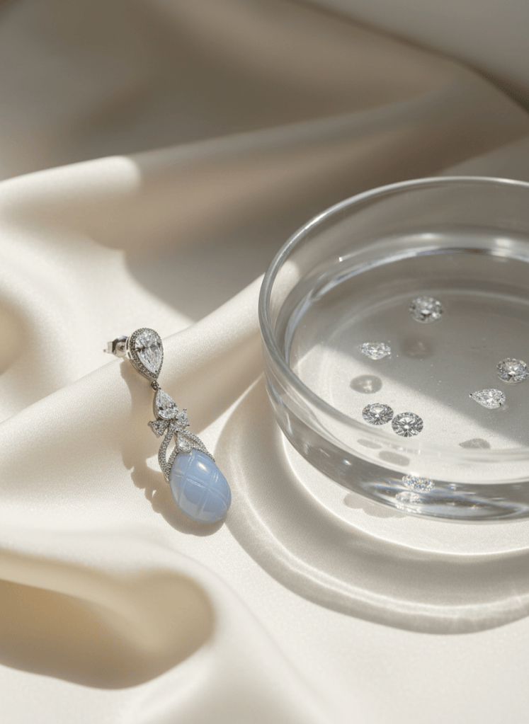 White gold diamond earring with a blue chalcedony drop beside rippled water, water-inspired high jewelry.