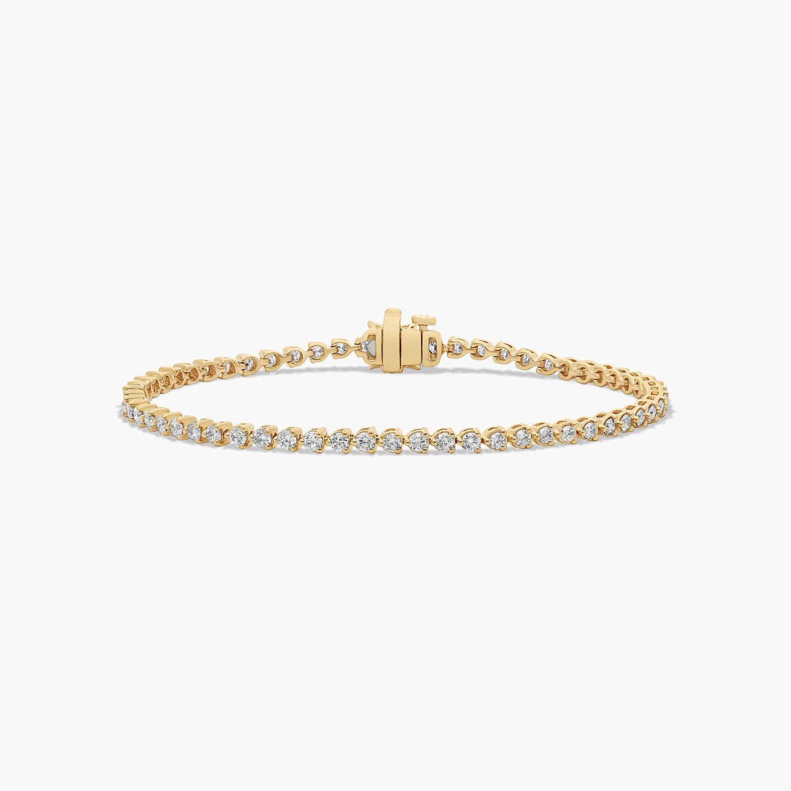 Tennis bracelet with a single row of round natural diamonds in three-prong baskets and a flower clasp, 14K yellow gold.