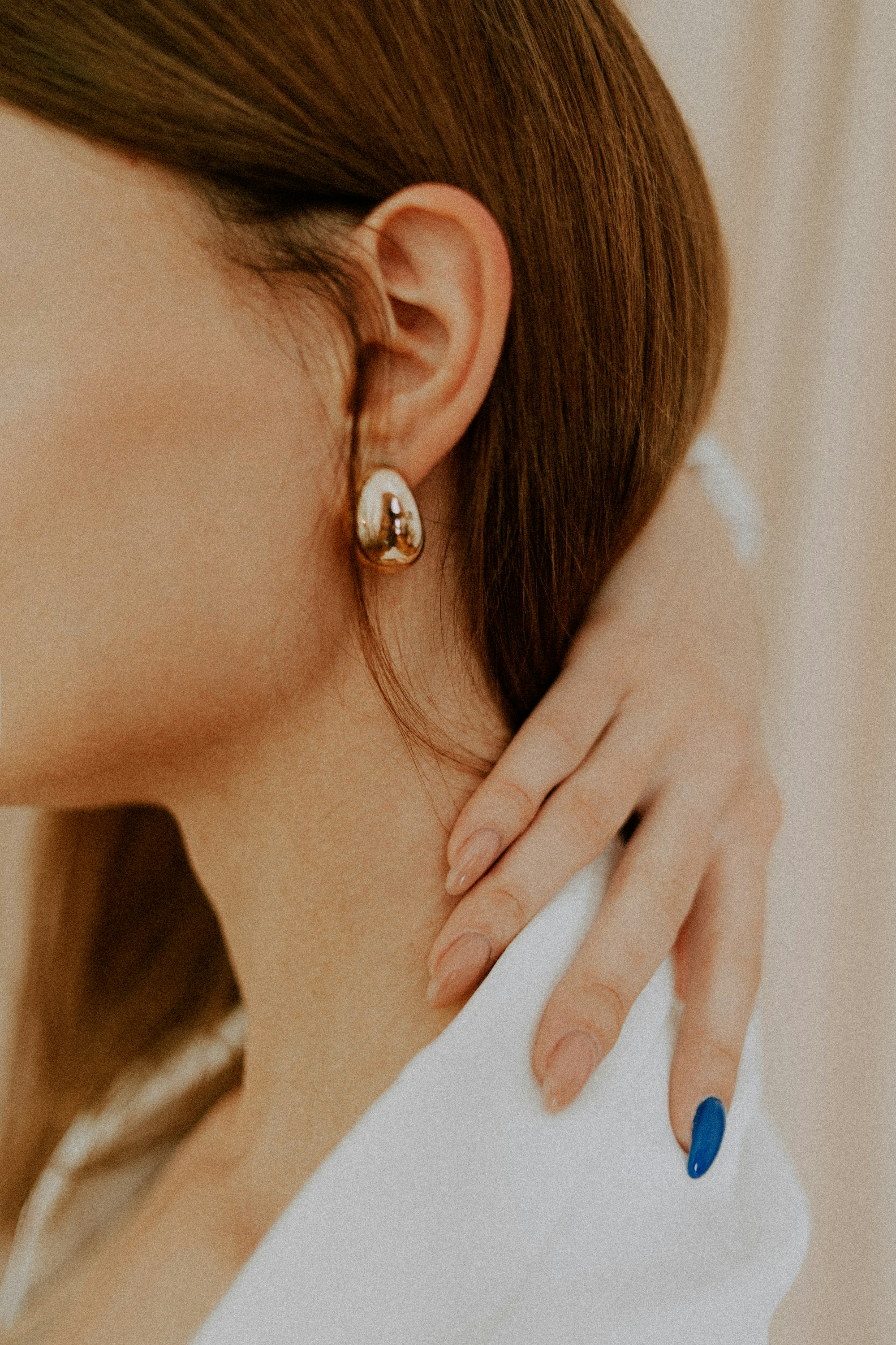 Close-up of a woman's ear wearing a round diamond stud earring.